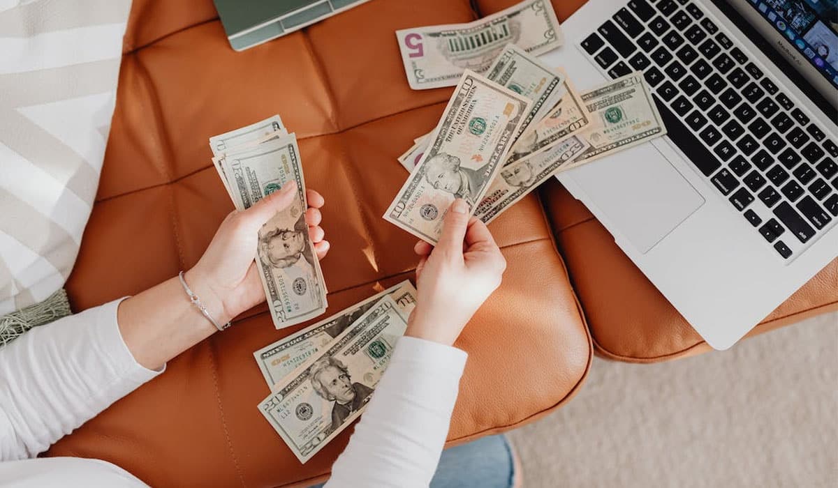 woman counting money bills on the couch