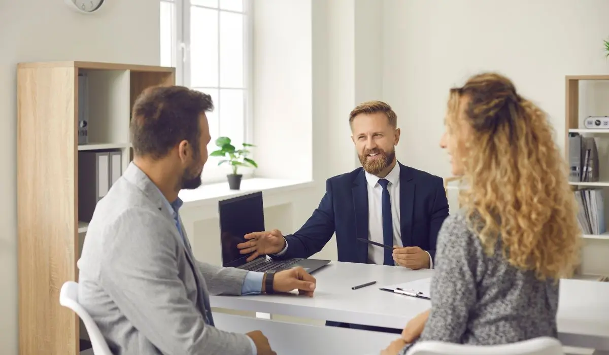 California property manager discussing lease agreements with a couple while screening tenants in a professional office.