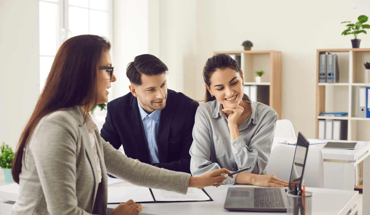 A professional property manager in Huntington Beach reviews documents with rental property owners in a modern office setting, highlighting trust and clarity.